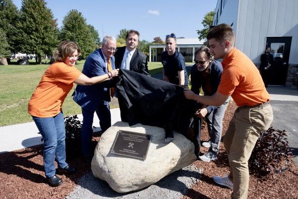 A plaque dedicating the campus pergola in honor of JP Ramel is unveiled.